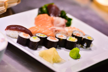 Great dish with Different Types of sushi and sauces. It is on a table in a restaurant during a dinner. Japanese food