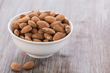 White Bowl With Almonds on Wood Background