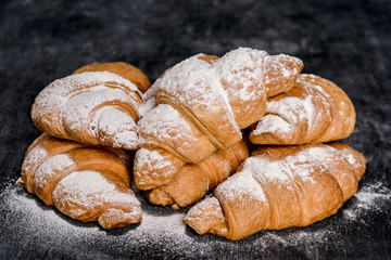 Macro picture of croissants with powdered sugar on grey table. 