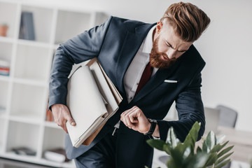 young businessman in suit holding documents and folders in office