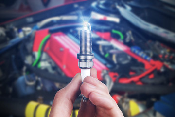 Mechanic holds a spare part spark plug in his hand. Auto part spark plug close-up.