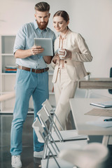 Fototapeta premium Young smiling business people using digital tablet together in office