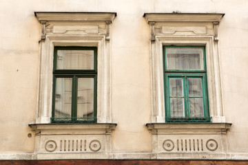 Two vintage design green windows on the facade of the old house