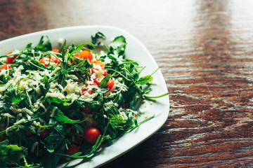 Fresh salad with tomato, ruccola on kitchen table.