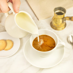 Milk poured into cup of coffee