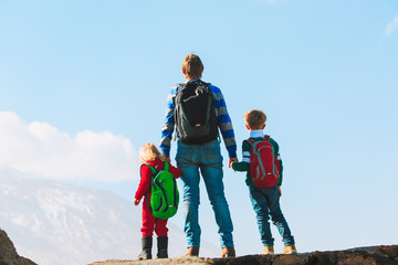 father and two kids travel hiking in mountains