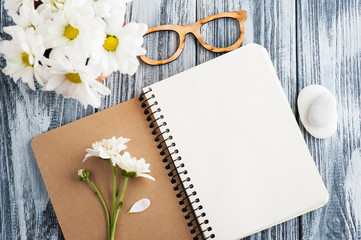 Open blank notebook, pebbles, flowers