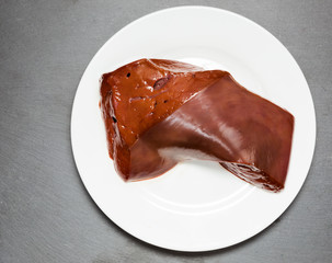 Beef damp liver on a white plate on a background of a stone board