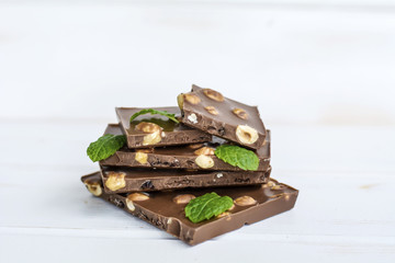Chocolate pieces with mint leaves on white wooden  background