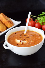 Tomato gravy [sauce] for meatballs in white bowl with white spoon on a black background. Healthy food concept.