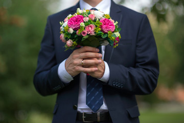 A beautiful bridal bouquet in the hands of the groom in a suit