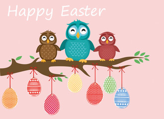 Easter eggs hang on ribbons. Lovely owls are sitting on a tree branch.
