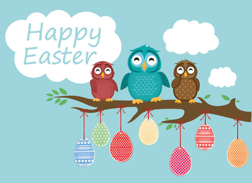 Easter eggs hang on ribbons. Lovely owls are sitting on a tree branch. Greeting card 
