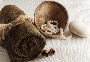 A rolled towel, tied with a rope and pearls in a coconut on a light woven napkin, preparation for a...