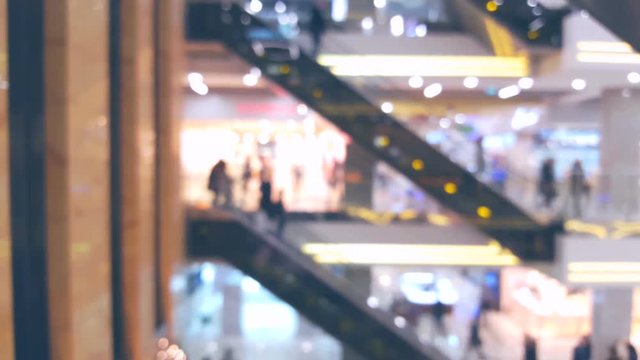 Shopping mall with many people on escalators, blurred defocused background
