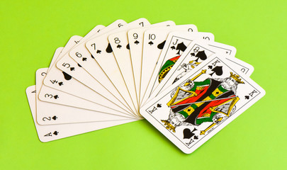 Play cards. All the spades isolated on green background.