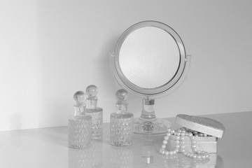 little mirror on a dresser rounded with fragrance bottles and casket - obrazy, fototapety, plakaty