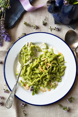 cucchiaio pieno di piccoli gnocchi verdi, con erbe aromatiche e crema bianca al formaggio