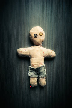 Voodoo doll with dramatic lighting on a wooden background