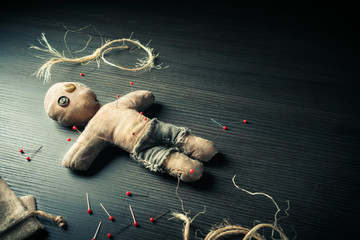 Voodoo doll with dramatic lighting on a wooden background