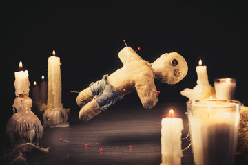 Voodoo doll with dramatic lighting on a wooden background - obrazy, fototapety, plakaty