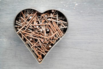 Heart shape filled with rusted nails, with a wooden light gray background, Father's Day, top view