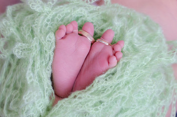 Wedding rings of parents on the feet of a newborn baby boy