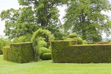 Trimmed, circle hedge with archway opening to an inner topiary garden .