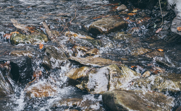Проточная вода горного ручья. Ледяная холодная вода и каменные глыбы