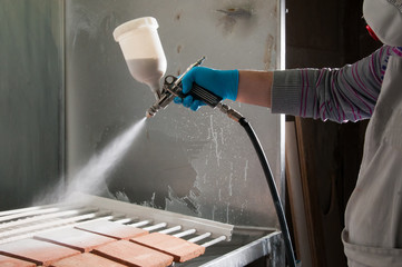 Pottery artisan in Caltagirone, Sicily, using an airbrush to enamel some square tiles