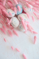Composition with blue easter eggs and pink bunny(rabbit) tail grass on white background. Selective focus. Easter background with copy space for advert or text