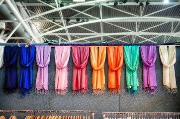 many pashmina foulards hanging from a market stall