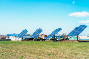 Solar panels on the green field in sunny weather. Vivid colorful image.
