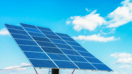 Solar panels on the green field in sunny weather. Vivid colorful image.