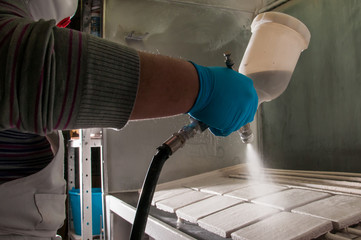 Pottery artisan in Caltagirone, Sicily, using an airbrush to enamel some square tiles