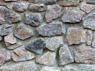 Stone wall from a large granite cobblestone close-up
