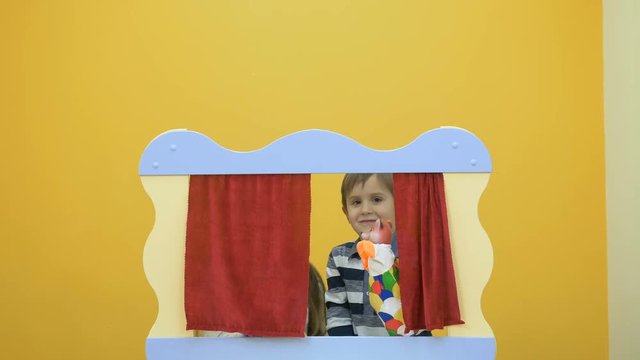 Little kids playing with puppets behind the screen in puppet show