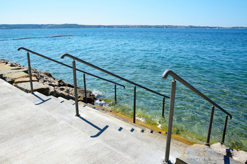 Stairs with railing into the clear sea.