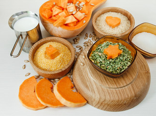 Cut Pieces of Pumpkin with Seeds,Cereals in the Wooden Plates and Pea.Milk,Harvest,Fresh Vegetable, Ingredient.White Food Background.