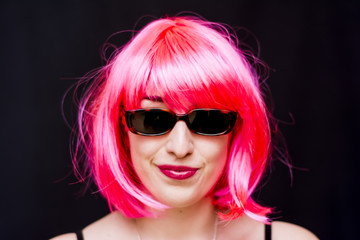 Naklejka premium Beauty Woman With Pink Wig And Sunglasses Over Black Background