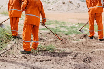 Workers using hoe to remove weeds. Construction of sidewalks