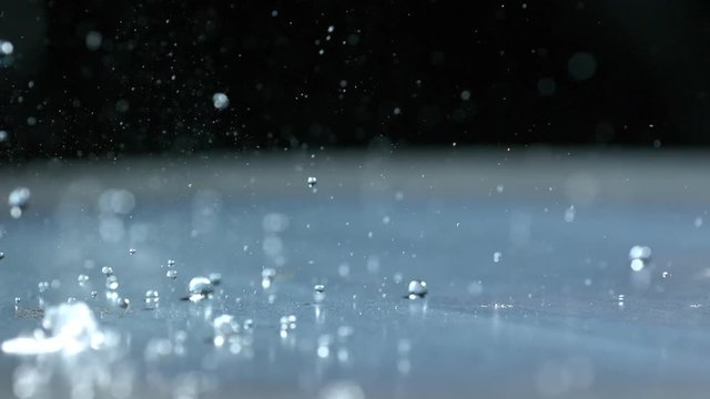 Slow motion of water droplets bouncing across a metal plate.