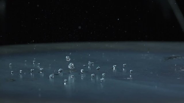 Slow motion of water droplets falling on metal surface.