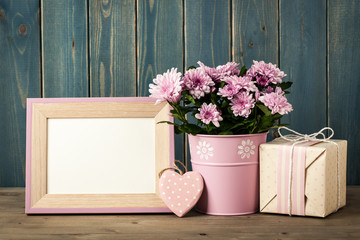 Fresh pink chrysanthemum flowers in bucket, gift box and blank frame