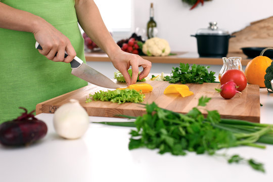 Close up of  woman's hands cooking in the kitchen. Housewife slicing ​​fresh salad. Vegetarian and healthily cooking concept