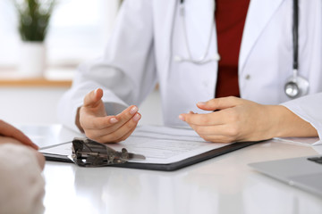 Fototapeta premium Close up of a doctor and patient hands while discussing medical records after health examination