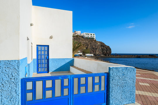 Blue Gate And White House On Promenade In Fishing Village Las Playitas On Southern Coast Of Fuerteventura, Canary Islands, Spain