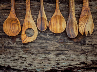 Various wooden cooking utensils border. Wooden spoons and wooden spatula on shabby wooden background with flat lay and copy space.