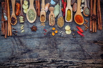 Various of spices and herbs in wooden spoons. Flat lay of spices ingredients chilli ,pepper corn, garlic, thyme, oregano, cinnamon, star anise, nutmeg, mace, ginger and bay leaves on shabby wooden.