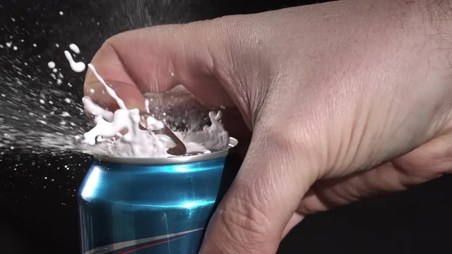 Slow motion of  can opening and spraying as tab is being pulled.